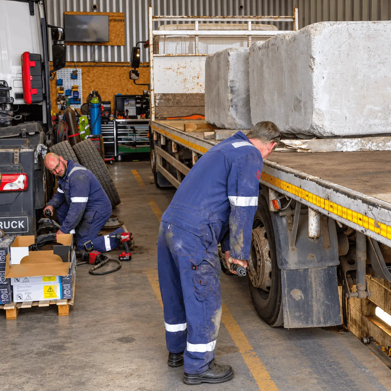 Mechanics repairing a loaded trailer